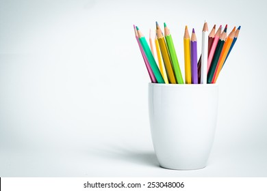 A group of color pencils in a white cup on an isolated background - Powered by Shutterstock