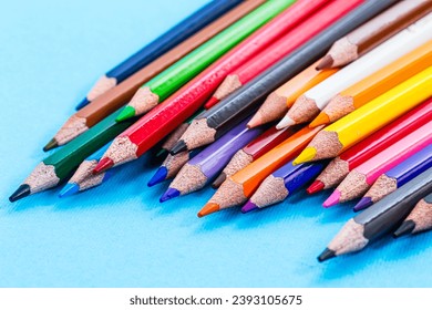 A group of colored pencils lined up on a blue surface - Powered by Shutterstock