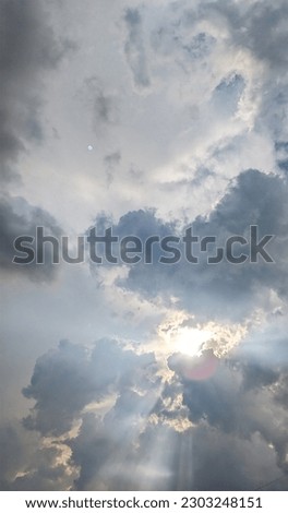 A group of colorful clouds in an afternoon sky, with a sunset hiding behind those clouds creates light ray 