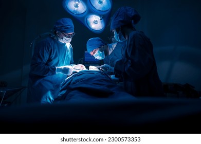 Group of concentrated surgical doctor team doing surgery patients in hospital operating theater. Professional medical team doing critical operations - Powered by Shutterstock