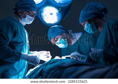 Group of concentrated surgical doctor team doing surgery patients in hospital operating theater. Professional medical team doing critical operations