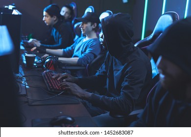 Group of concentrated young software developers in dark outfits sitting in row and working in server center