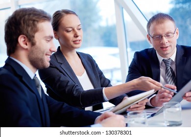 Group of confident business partners discussing paper at meeting