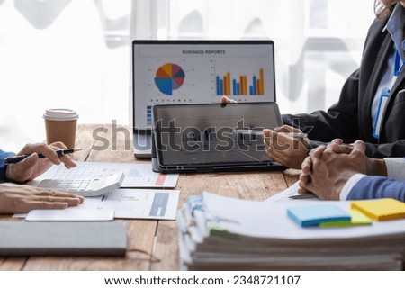 Group of confident business people point to report graphs and financial charts analyze market data, balance sheet, account, net profit to plan new sales strategies to increase production capacity.