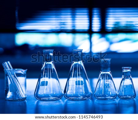 group of conical flasks containing shiny in blue chemistry science laboratory background