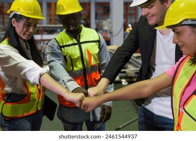 Group of construction workers clad in hard hats and reflective vests, are locked in a cordial fist bump, signaling joint progress. Workers working in the metal sheet factory. - Powered by Shutterstock