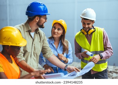 Group Construction workers looking at blueprints on construction site. Team of architects and civil engineers inspecting construction site. Architect with work vests discuss the construction process. - Powered by Shutterstock