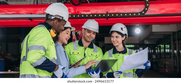 A group of construction workers are smiling and looking at a piece of paper. They are wearing safety gear and are standing in front of a red building