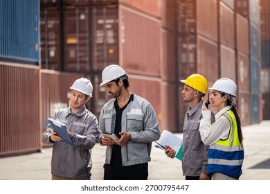 A group of construction workers are standing in front of a large container. They are all wearing hard hats and holding papers