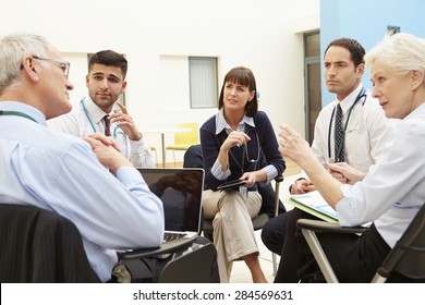 Group Of Consultants Sitting At Table In Hospital Meeting