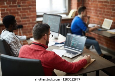 Group of contemporary it-engineers sitting b ydesks in front of computers and learning new software or codes - Shutterstock ID 1283022979