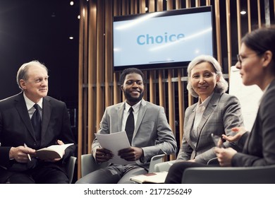 Group Of Content Multi-ethnic Colleagues Sitting In Circle And Brainstorming About Strategy At Meeting