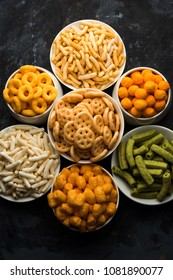 Group of Corn Puff, cheese balls and rings, crispy salty Wheel fryums, puffed rice and potato in macaroni shape with plain/spinach flavour, chatpata masala and crunchy fried snacks served in bowls 