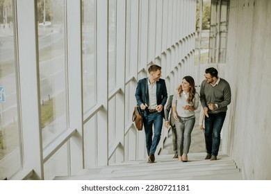 Group of corporate business professionals climbing at stairs in office corridor on a sunny day