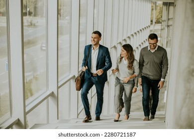 Group of corporate business professionals climbing at stairs in office corridor on a sunny day