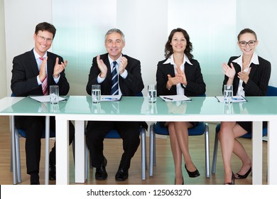 Group of corporate recruitment officers interviewing for a professional vacancy applauding