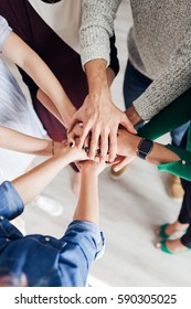 Group Of  Co-workers  Standing In A Circle With Their Hands In A Huddle