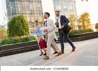 Group Of Coworkers Walking Outside In Front Of Office Buildings.