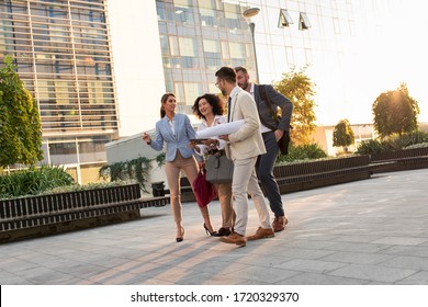 Group Of Coworkers Walking Outside In Front Of Office Buildings.