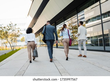 Group Of Coworkers Walking Outside In Front Of Office Buildings Discuss About Business Plan.