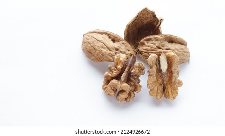 A group of a cracked half brown raw walnuts nuts and splintered walnut shell isolated on white background. nut hard shells, top view