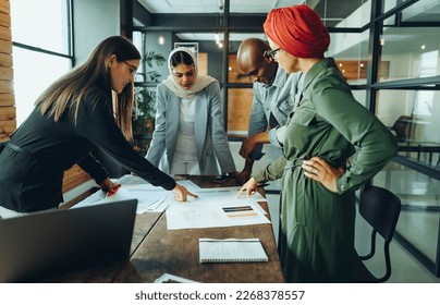 Group of creative interior designers discussing colour palettes during a meeting in a modern office. Team of multicultural businesspeople sharing innovative ideas in an inclusive workplace. - Powered by Shutterstock