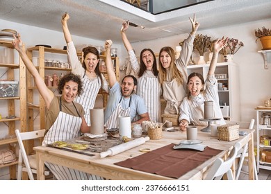 Group of creative people in aprons posing together while having fun in a pottery class. Hobby and craft concept. - Powered by Shutterstock