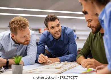 Group of creative people working together in office. Casual team of young architect and engineers working on scale model house. Mid adult man working on project while giving presentation to client. - Powered by Shutterstock