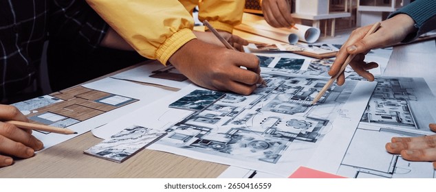 A group of creative professionals engages in a collaborative design session, using blueprints and models to develop innovative architectural ideas and concepts. SACTR
