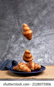 Group Of Croissants Falling On A Blue Plate. Healthy Breakfast. Sweets And Desserts