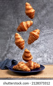 Group Of Croissants Falling On A Blue Plate. Healthy Breakfast. Sweets And Desserts