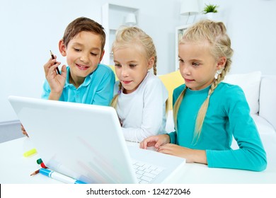 Group Of Curious Children Watching Stuff On The Laptop Screen