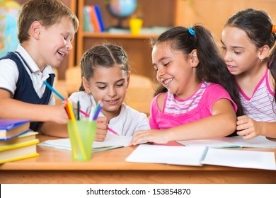 Group Of Cute Schoolchildren Drawing And Having Fun In Classroom