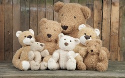 A Group Of Cute Teddy Bears Sitting Together Against An Old Wooden Wall