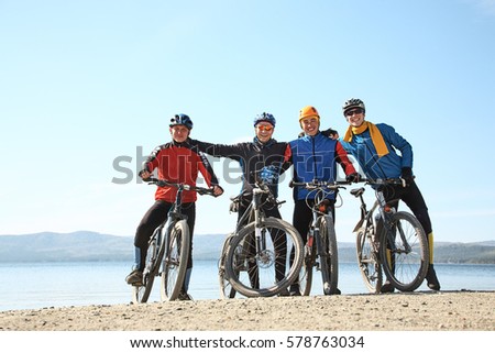 group of cyclists on a shore of a mountain lake. team outdoors. mountain bike