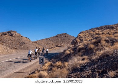 A group of cyclists rides along a winding road through the arid, rocky landscape near Kashan, Iran. The clear blue sky, sunny day and rugged terrain highlight the adventurous spirit of the journey. - Powered by Shutterstock