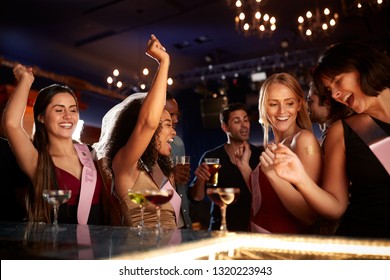 Group Of Dancing Female Friends Celebrating With Bride On Hen Party In Bar