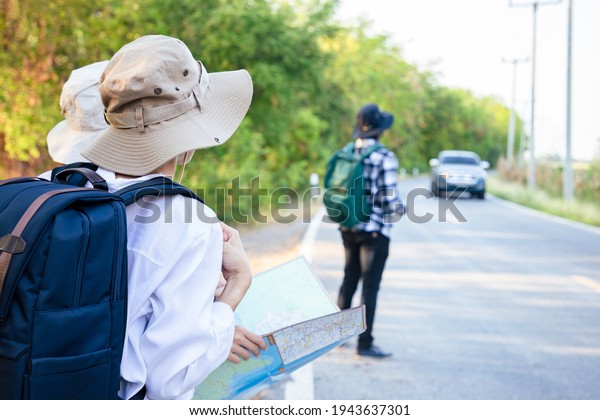Group of dear friends holding own drawing map and\
traveling to natural attractions and the public park near roadside.\
Journey of travel and environment studies. Search and finding\
location. Lost way