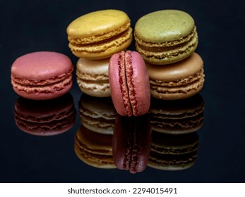 A group of delicious and colorful macarons are reflected on the glossy black support base