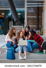 Group of delighted Asian female students gathering on stairs in university campus and doing homework together while using laptop. Concept for close friend of teens life.