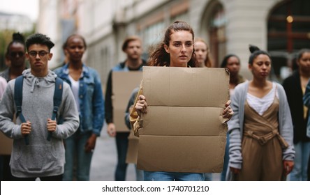Group of demonstrators with blank banner protesting on the street. Protestors doing demonstration on the street holding sign boards. - Shutterstock ID 1740701210