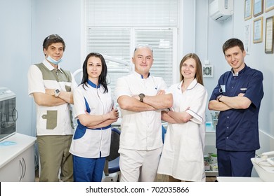 Group Of Dentists Standing In Their Office And Looking At Camera.