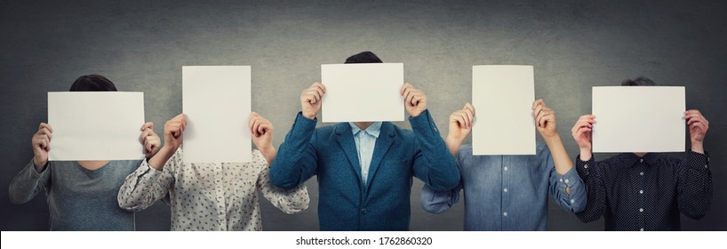 Group of different people, business team, each covering his face using a blank white paper. Teamwork thinking and cooperation process. Persons hiding identity behind an empty sheet, anonymous concept.