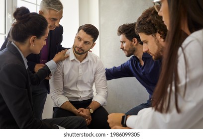 Group Of Different People Sitting In A Circle Supporting And Comforting A Sad Upset Young Man. Concept Of Psychological Help, Group Therapy And Overcoming Problems Together