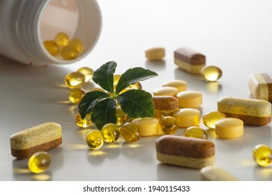 A group of diffrent pills with a green leaf on white background. As a concept of natural medicines. Preventive medicine.