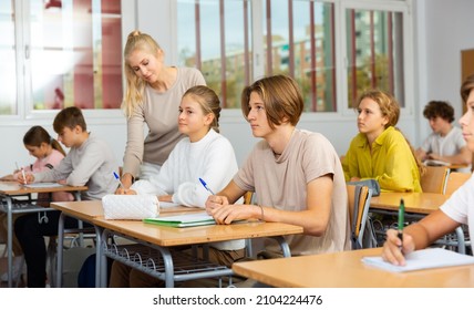 Group Of Diligent School Kids And Teacher During Lesson In Classroom In Secondary School