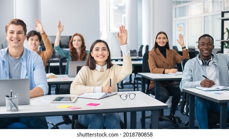 Group Discussion Concept. Smiling Diverse Students Raising Hands Asking Lecturer A Question, Using Computers Listening To Lecture At The University. Multiethnic Group Of Modern Students At Classroom