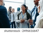 Group of diverse business professionals, businessmen and businesswomen, networking at a conference event. They are smiling, conversing, and engaging in discussions during a daytime seminar.