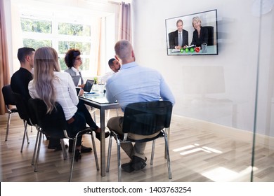 Group Of Diverse Businesspeople Looking At Television While Video Conferencing In Boardroom