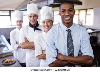 Group Of Diverse Chefs And Manager Standing With Arms Crossed In Kitchen At Hotel